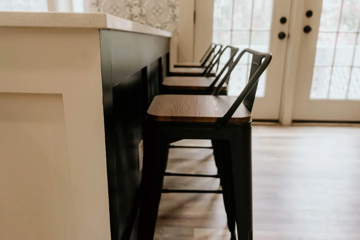 A warm, sociable space featuring a countertop with bar stools, double doors that potentially open to an exterior area, and abundant light. The inviting setup encourages shared stories, celebratory toasts, and casual meals, ideal for group gatherings.